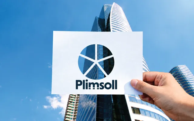 Hand holding a Plimsoll card with a cut-out pie chart divided into five segments, revealing parts of the same office building behind each segment.