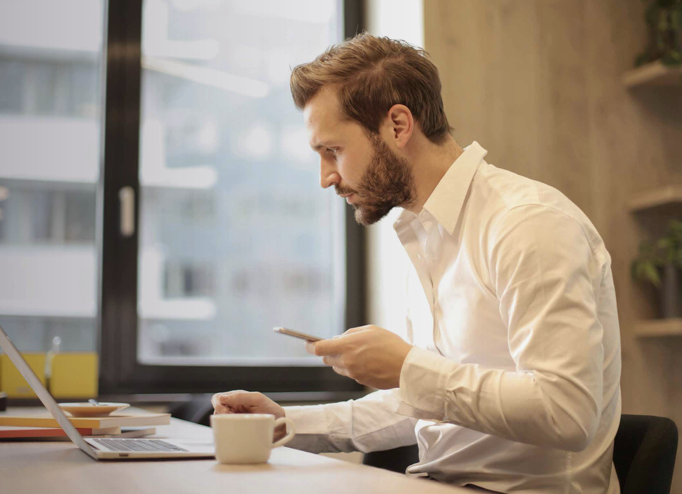 Person working at a desk using a laptop and phone